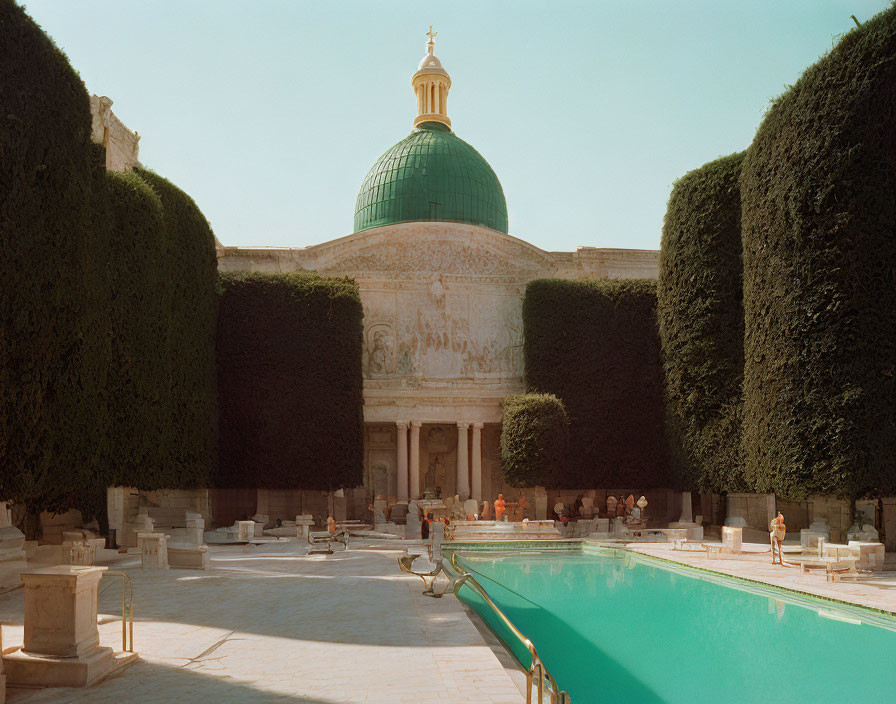 Green-domed building with pool and hedges under clear sky