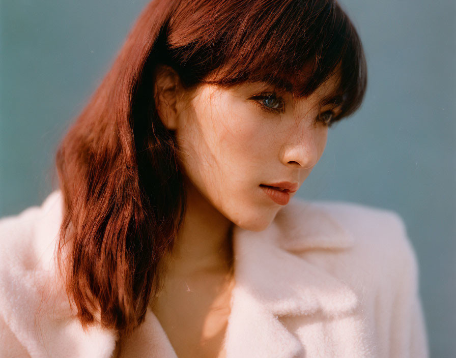 Woman with Shoulder-Length Brown Hair in Light Pink Coat on Blue Background