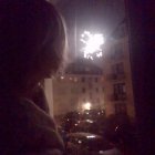 Children watching colorful fireworks through window on starry night.