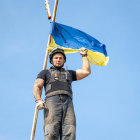 Uniformed person with blue and yellow flag and emblem against clear sky
