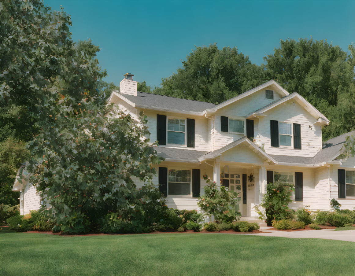 White Two-Story House with Gabled Roof Surrounded by Trees and Lawn