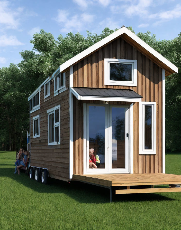 Compact wooden tiny house on wheels with large windows and front deck, featuring two people outdoors amidst lush green