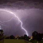 Dramatic thunderstorm with multiple lightning strikes above rural buildings