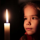 Curly-Haired Child Gazing at Lit Candle in Dimly Lit Scene