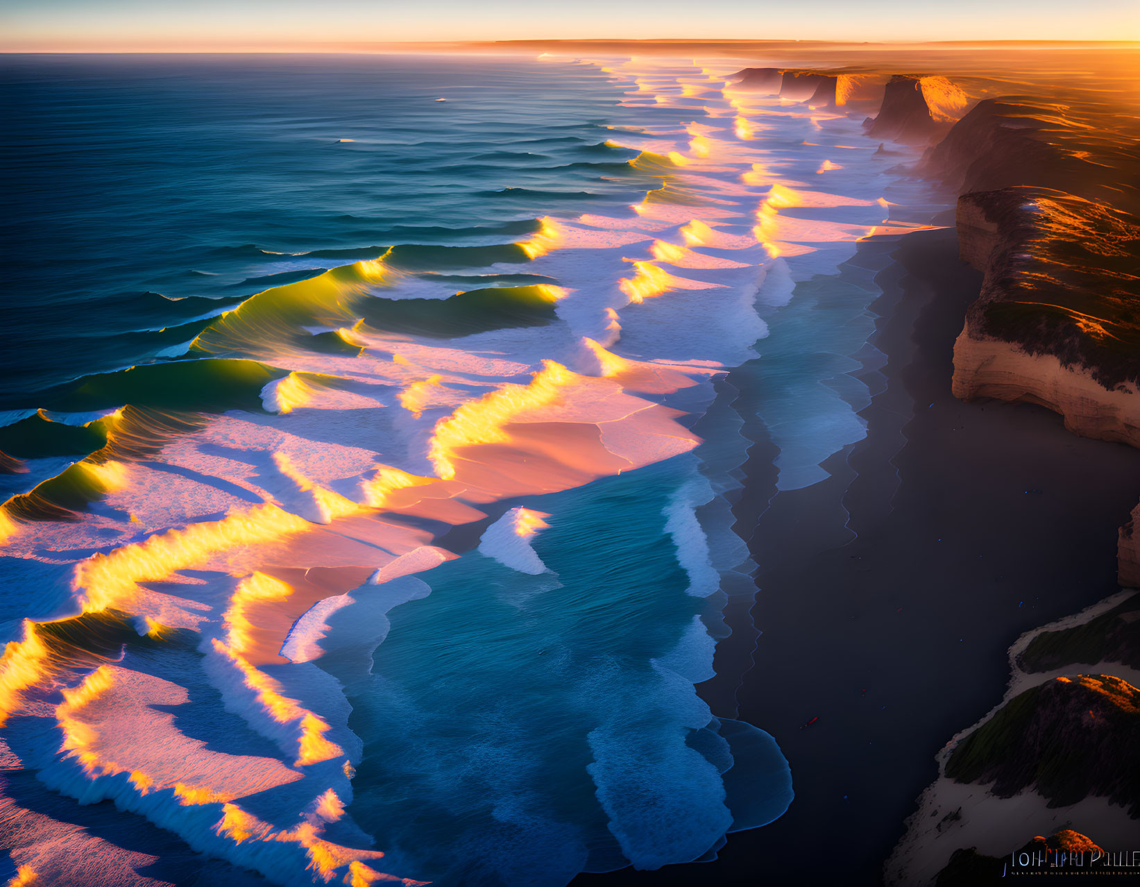 Sunset aerial view: Coastline with golden light on waves and cliffs