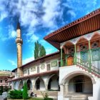 Traditional mosque with tall minaret in lush setting under blue sky