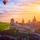 Sunset over medieval town with stone walls, towers, and hot air balloon