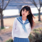 Smiling young woman in sailor-style school uniform with long, curly hair