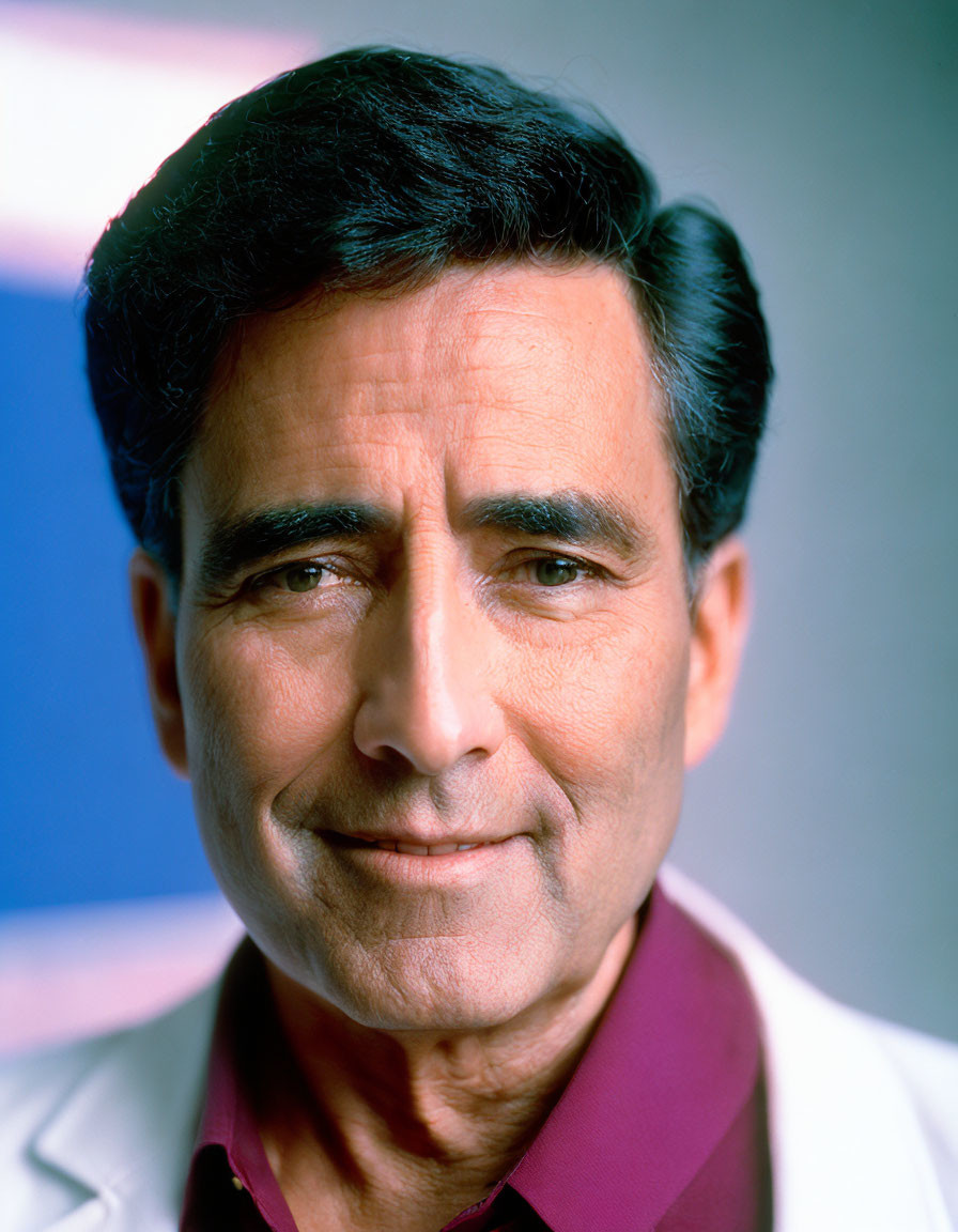 Smiling middle-aged man in lab coat and red shirt on blue background