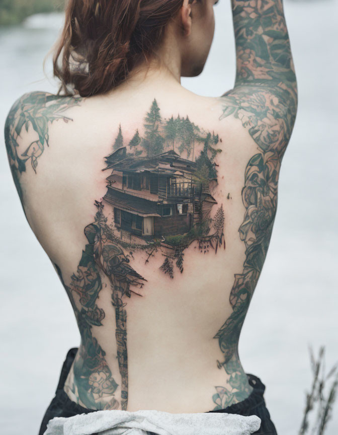 Detailed back tattoo of cabin in nature.