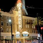 Ornate theater facade with neon signage, palm trees, and pickup truck at night