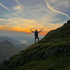 Person in adventure gear on mountain with paragliders at sunset