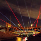 Colorful Light Beams Illuminate Nighttime City Bridge