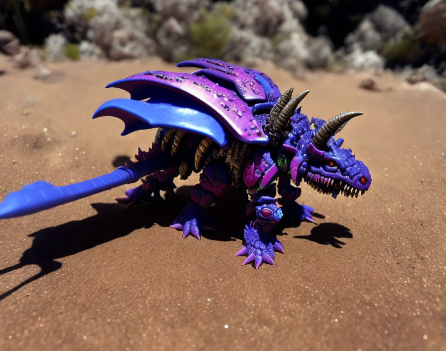 Colorful Toy Dragon with Purple and Blue Scales on Sandy Background