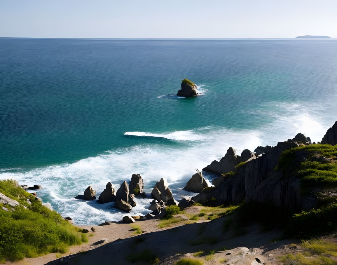 Rocky shoreline with lone formation, crashing waves, clear sky