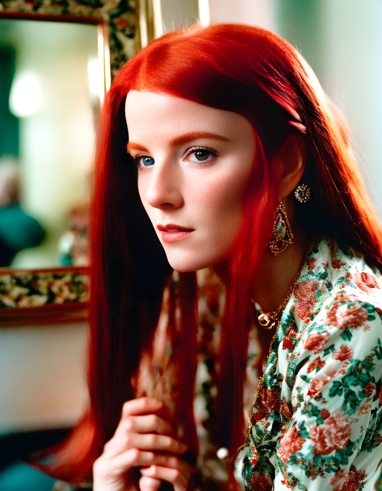 Vibrant red-haired woman in floral garment gazes at camera with reflection in mirror