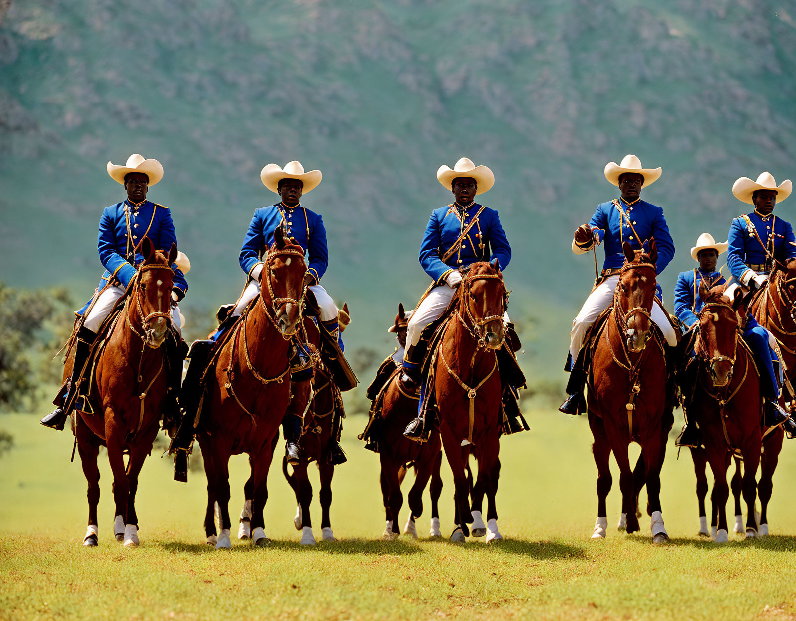 Blue Uniformed Horse Riders on Brown Horses Against Green Hills