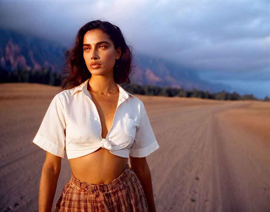 Woman on Sandy Beach at Twilight with Mountains in Background