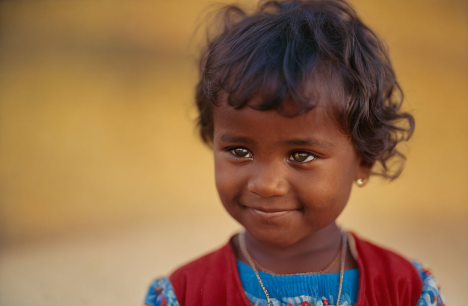 Smiling young child in red garment with blue-patterned neckline