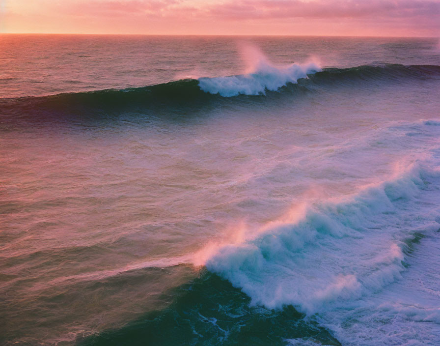 Ocean waves crashing under colorful sunset sky