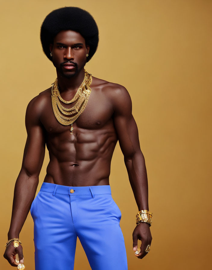 Shirtless man with afro in blue trousers and gold accessories