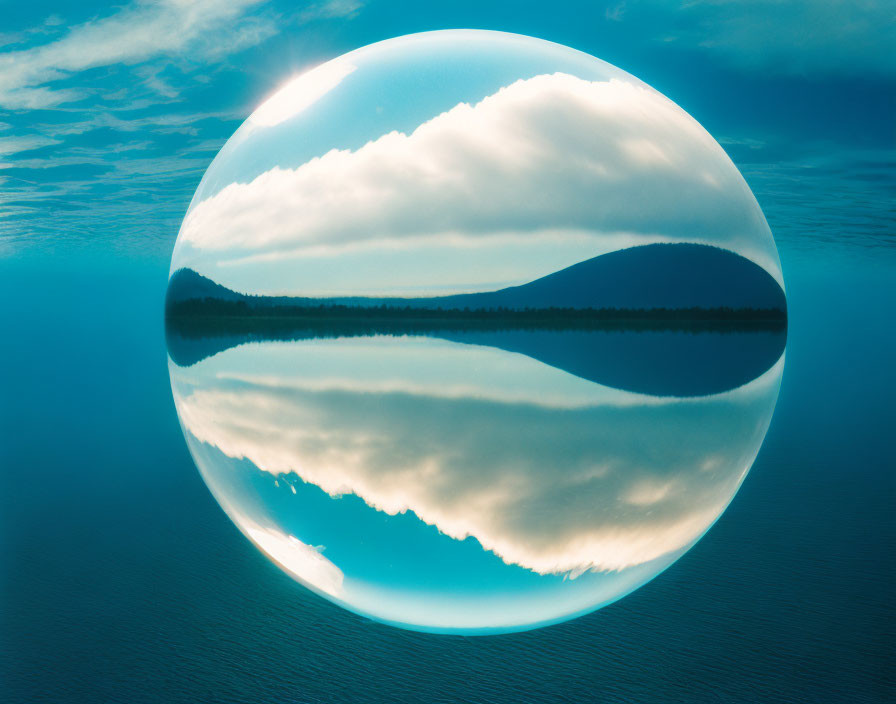 Tranquil landscape with lake, hill, and blue sky reflected in crystal ball