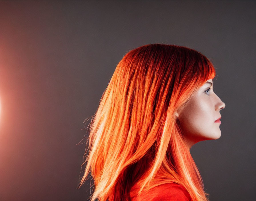 Vibrant red hair woman in side profile against gray background