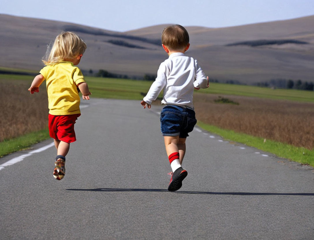 Children running joyfully in grassy landscape under clear sky