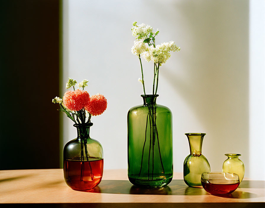 Colorful Glass Vases with Flowers on Wooden Surface