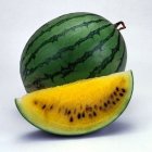 Striped green watermelon with yellow flesh and black seeds.