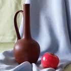 Brown jug on blue swirly backdrop with red flower.