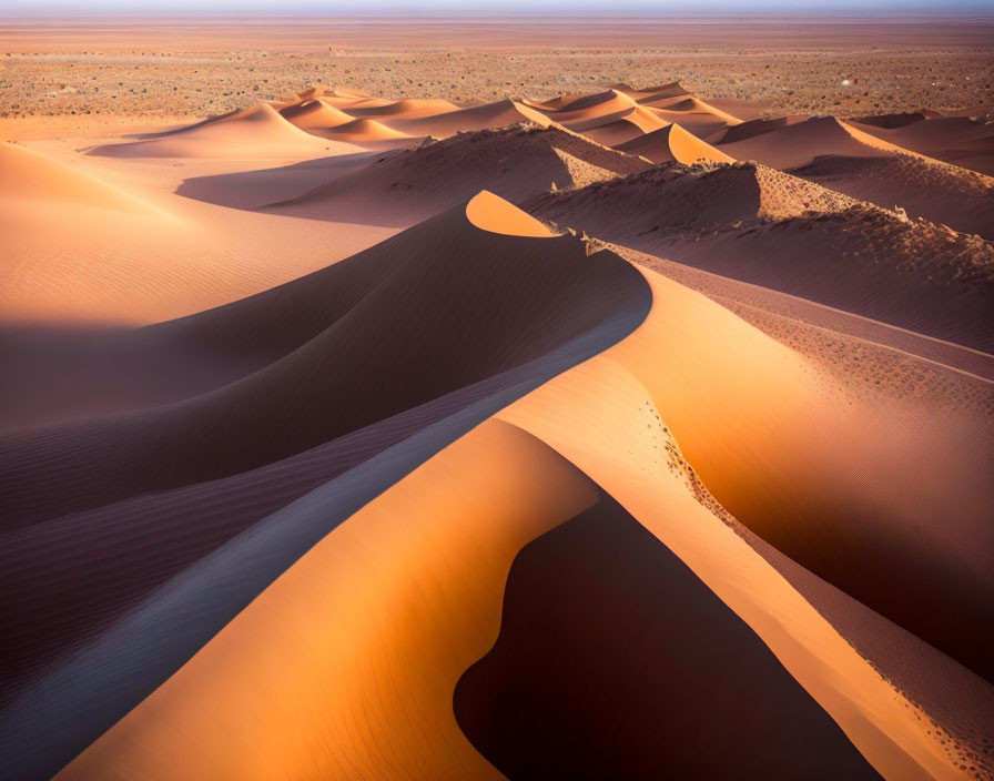 Smooth golden sand dunes in vast desert landscape at dusk