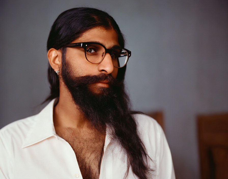 Bearded man in glasses and white shirt on blue background