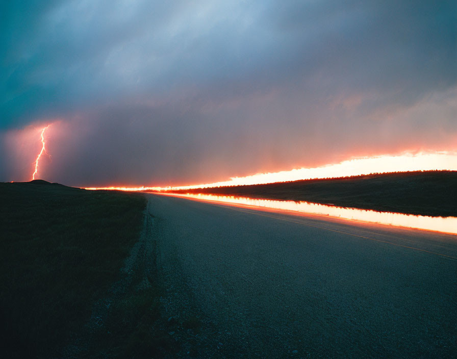 Twilight lightning strike reflected in roadside water at serene landscape