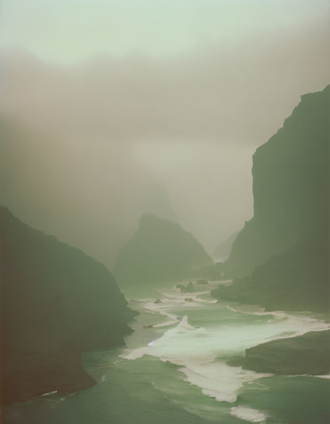 Misty mountain landscape with winding river in green-tinted fog