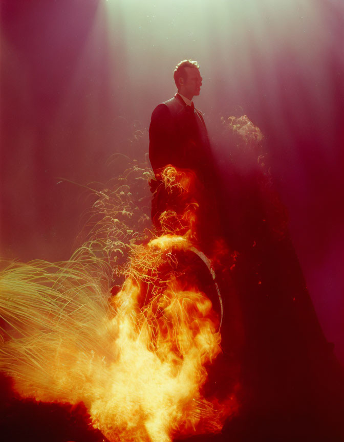 Man standing in vibrant flames and smoke with dramatic light rays