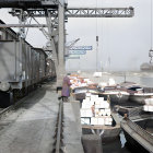 Woman in cloak walking near snowy dock with cargo boats and industrial cranes in foggy setting