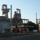 Rusted industrial facility with towers, pipes, and machinery in soft sunlight