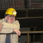 Tired person with grizzled beard in dirty helmet in industrial background