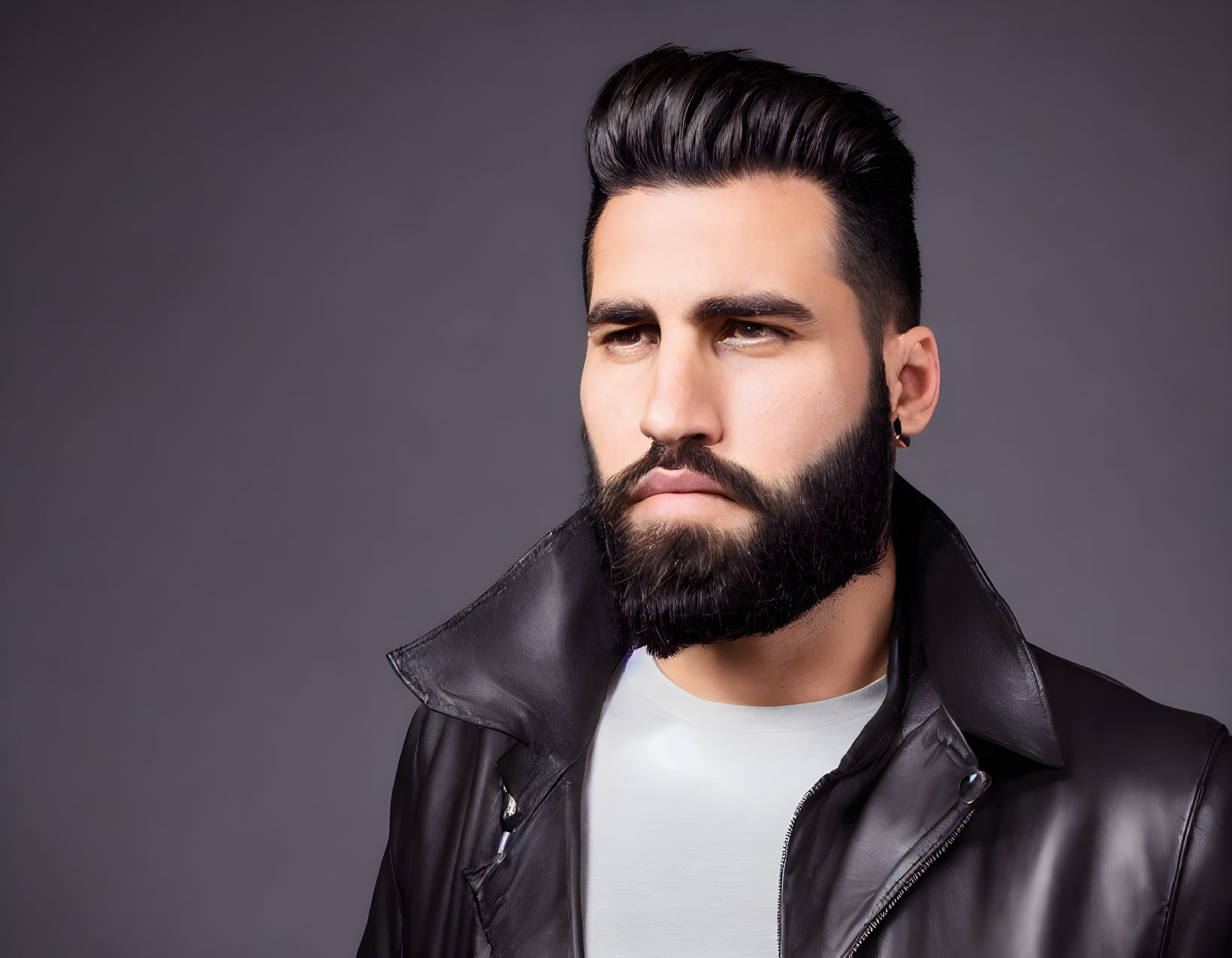 Bearded man in leather jacket with styled hair on gray background