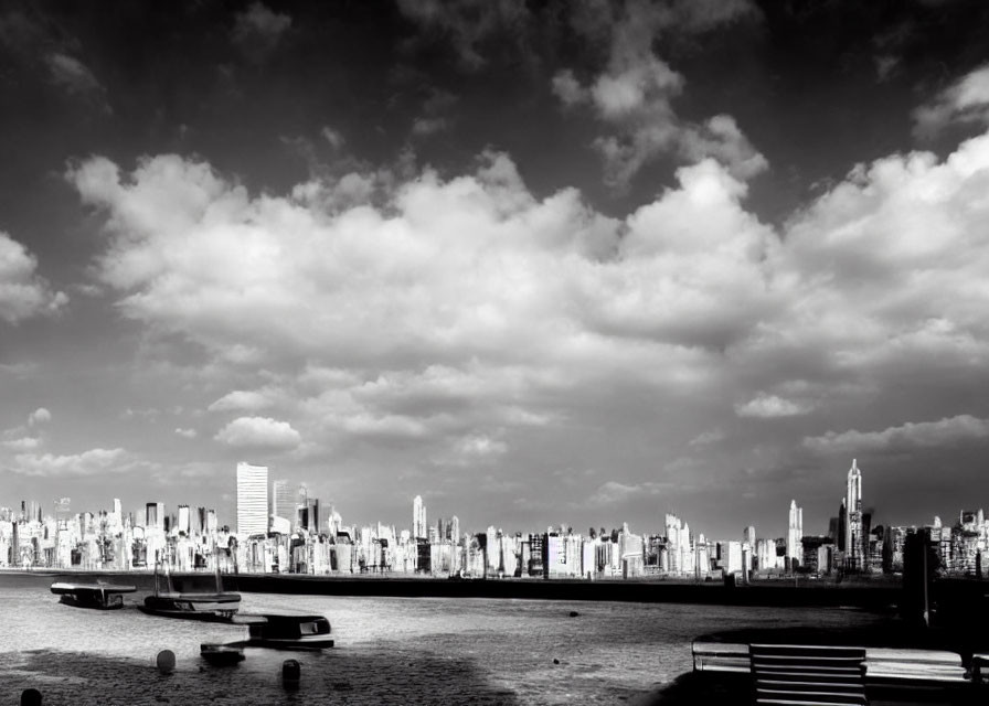 Monochrome city skyline with clouds and boats in foreground