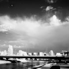 Monochrome city skyline with clouds and boats in foreground