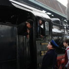 Vintage attire passengers interacting with conductor on classic steam locomotive in snowfall