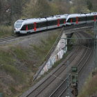 Modern Train Crossing Stone Arch Bridge in Lush Rocky Landscape