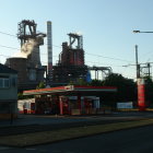 Vintage steam train on tracks with illuminated factories at dusk