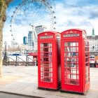 Vintage Red Phone Booths, Snowy Backdrop, Person in Red Coat, Quaint House,