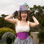 Steampunk-themed woman in top hat, corset, and gloves against leafy backdrop