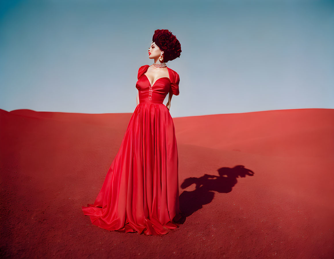 Woman in flowing red dress stands in desert with elegant updo hairstyle