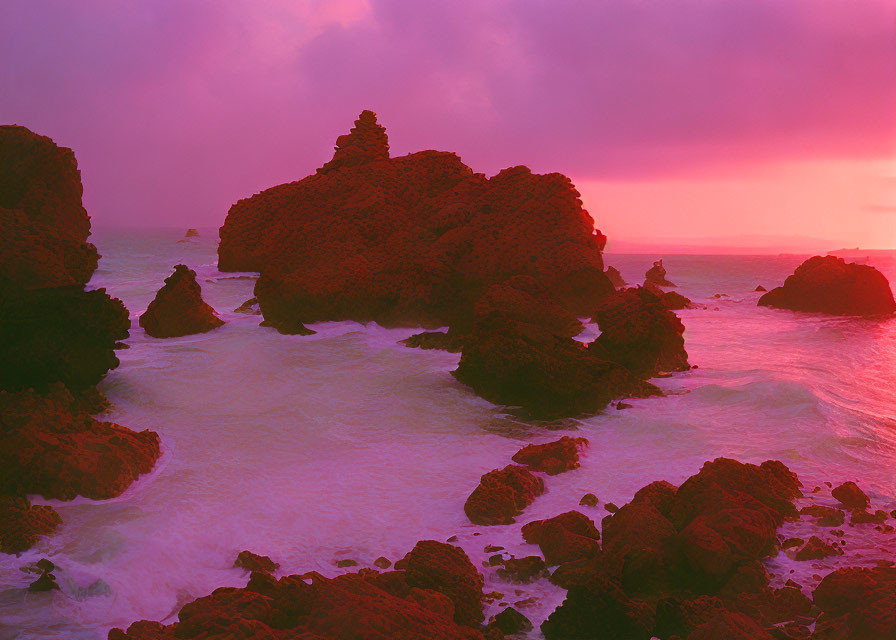 Surreal sunset over rocky shoreline with purple and pink hues