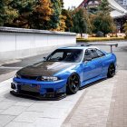 Blue Modified Sports Car with Racing Stripes and Rear Wing Parked in City Street